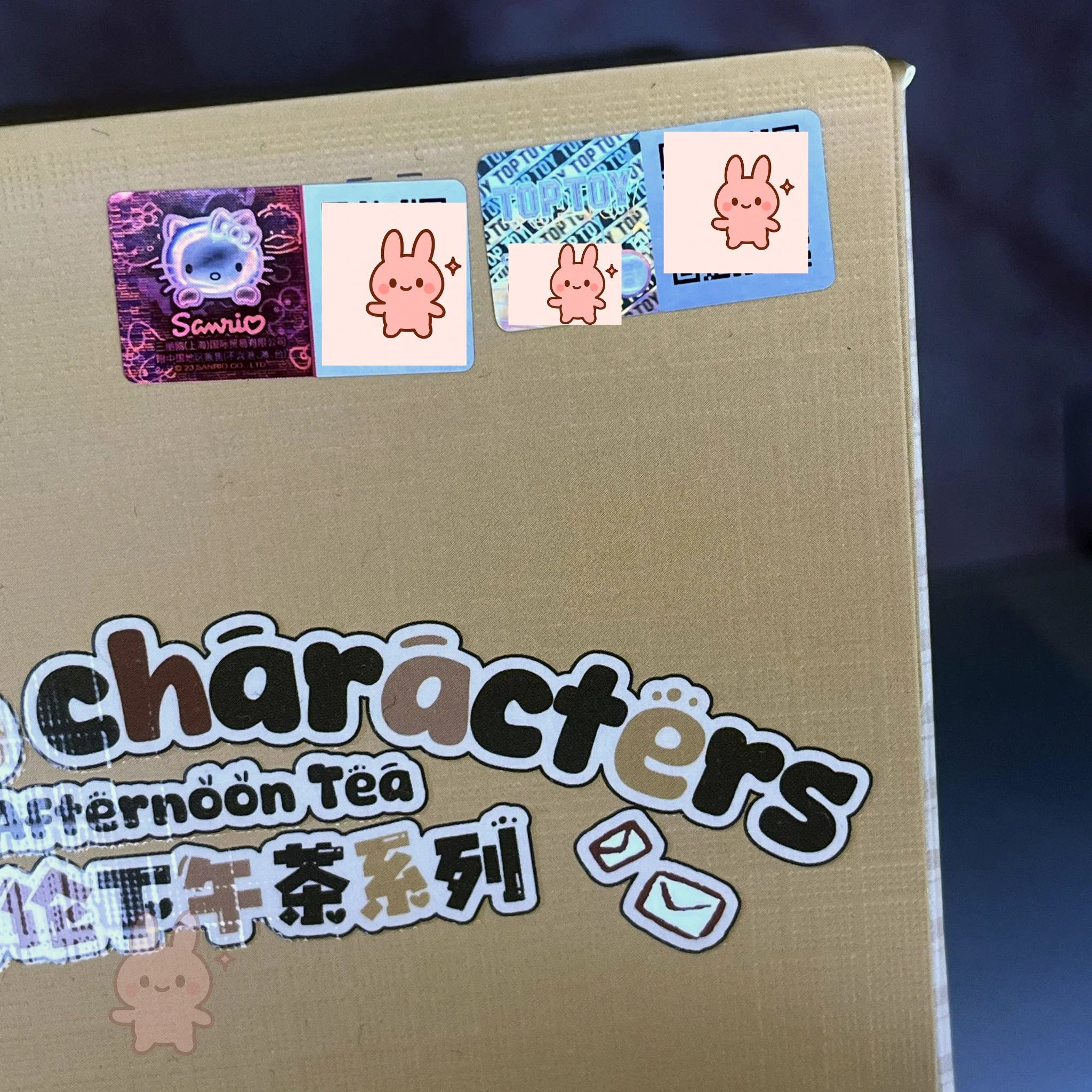 Cardboard box with 'characters Afternoon Tea' text and colorful stickers on a dark background