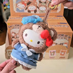 sanrio-afternoon Plush keychain of a character with a blue outfit and red bow, held in front of a box with more plush toys.
