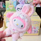 Sanrio characters Elf Bunny Baby Plush keychain with a cartoon character held by a hand, with colorful boxes in the background.